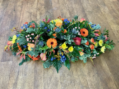 Warm Embers - A gorgeous tribute consisting of warm orange tones, yellows and dusky blues- including gerberas, thistle, calla lilies, berries and much more.