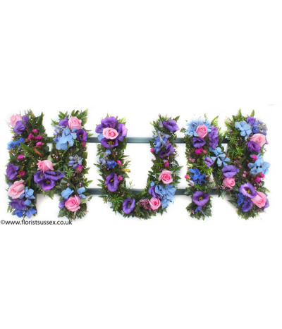 MUM 03 - Loose lettering, meaning that the letters are filled with greenery and mixed flowers in a more natural style. This example includes striking purple, blue and pink seasonal flowers.
Any wording can be created in this style, and colours can be altered to suit your preferences- please call us to discuss.