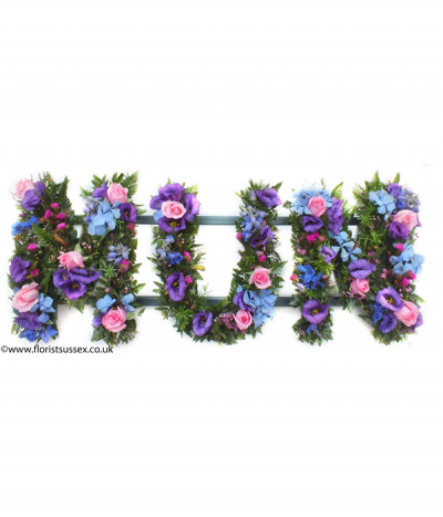 MUM 03 - Loose lettering, meaning that the letters are filled with greenery and mixed flowers in a more natural style. This example includes striking purple, blue and pink seasonal flowers.
Any wording can be created in this style, and colours can be altered to suit your preferences- please call us to discuss.