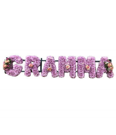Six-letter name tribute (Gramma) - Lettering "Gramma" massed in pink chrysanthemums, finished with dainty pink and white sprays at each end and individual pink roses. 
Any wording can be created in this style, and colours can be altered to suit your preferences- please call us to discuss or note your six-letter name in the "any special requests" box to order online.
£45.00 per letter.