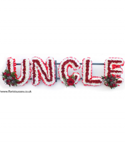 Uncle - "Uncle" lettering massed in deep red and white chrysanthemums, framed with red pleated ribbon edging and complimented with red flower sprays.
Any wording can be created in this style, and colours can be altered to suit your preferences- please call us to discuss.
£45.00 per letter.