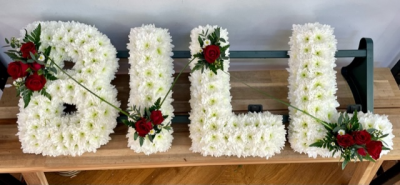 Four-letter name tribute (Bill) - Example lettering "Bill" massed in white chrysanthemums with red rose sprays on each letter with decorative grass loops. 
Any wording can be created in this style, and colours can be altered to suit your preferences- please call us to discuss your requirements or note your four-letter name in the "any special requests" box to order online. 
£45.00 per letter.
