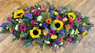Splash of Sunshine - Lots of bright mixed colours make up this vibrant tribute, consisting of seasonal flowers such as sunflowers, roses, gerberas, carnations, lisianthus and much more.