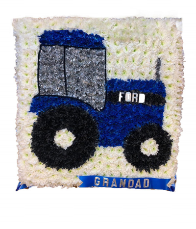 Ford Tractor Tribute - A 2D Ford Tractor design in blue dyed chrysanthemums with silver and black details and a white massed background, framed with blue pleated ribbon edging. A name or word on a ribbon