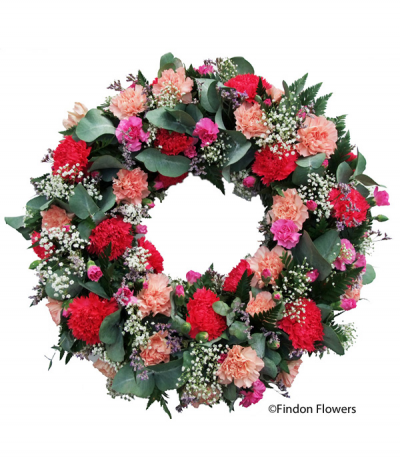 Carnation Wreath - A pretty wreath design consisting of mixed pink, peach and red carnations and spray-carnations, complimented with gypsophila and mixed seasonal foliage.