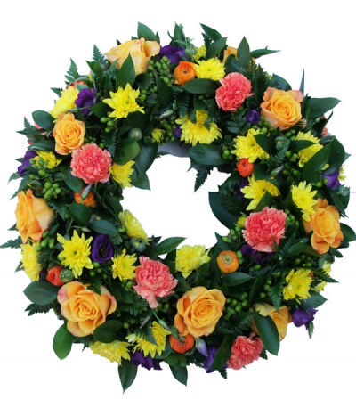 Colour Zest Wreath - A colourful selection of seasonal mixed flowers amongst lush foliage for a classic yet striking tribute to a loved one.