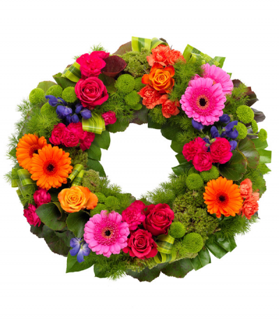 Kaleidoscope Wreath - A striking wreath tribute full of gloriously intense colour, featuring gerberas, roses, carnations and aconitum against a vibrant backdrop of lime green pom-pom chrysanthemums