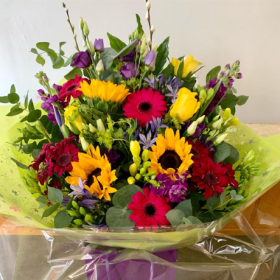 Rise & Shine - A gorgeous front-facing handtied bouquet in water presented in a gift bag/box. Created using a bright seasonal selection including purple, yellow and hot-pink flowers.